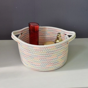 Close-up of a white cotton rope basket with rainbow stitching and double handles for storage