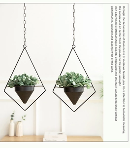 Detail of two geometric diamond-shaped iron hanging planters with faux greenery