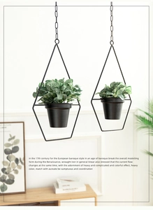 Detail of two black geometric metal hanging planters with chain and indoor greenery