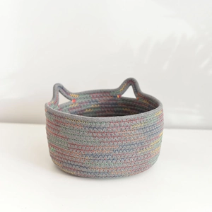 Close-up of cat-ear handles on a woven cotton rope basket with rainbow stitching details
