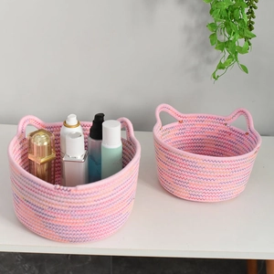 Detailed view of pink cotton rope woven storage baskets with cat ear handles on a desk