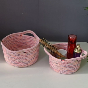Macro detail of two pink woven cotton storage baskets with decorative zig-zag stitching