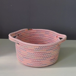 Detail view of pink cotton rope storage basket with decorative zigzag stitching and handles
