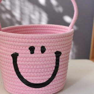 Close-up of pink cotton rope basket with woven handle and smile face embroidery detail