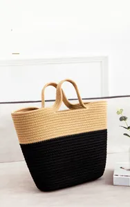 Detail of handmade woven cotton tote bag in beige and black displayed on a sofa
