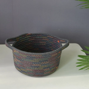 Close-up of a dark grey woven cotton storage basket with colorful zigzag stitching detail