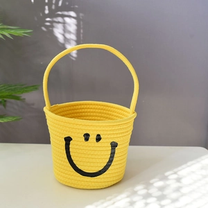 Detail of a yellow woven cotton rope basket with a smiley face and a single handle