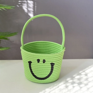 Close-up of green cotton rope storage basket with handle and minimalist smiley face