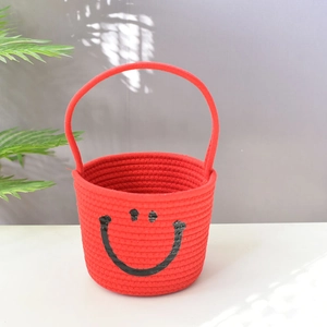 Detail of red woven cotton rope storage basket with black smiley face and handle