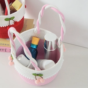 Detail of hand-woven cotton storage basket featuring cute cherry decor and pink-white weave
