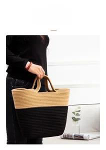 Close-up of a two-tone woven cotton rope tote bag in beige and black held by a person