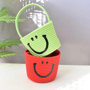 Detailed view of green and red woven cotton rope storage baskets with cute black smiley faces