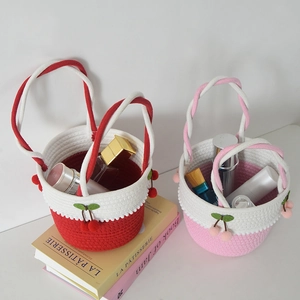 Detail of cherry straw tote bag with white cotton tassels and red pompom decorations