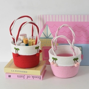Detail of handmade woven cotton storage baskets with cherry charms and white pom-poms