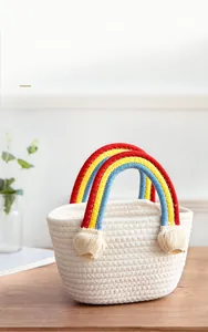 Close-up of rainbow cotton rope handle and beige tassel on white woven straw bag