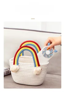Close-up of handmade white cotton rope basket with vibrant rainbow tassel handles