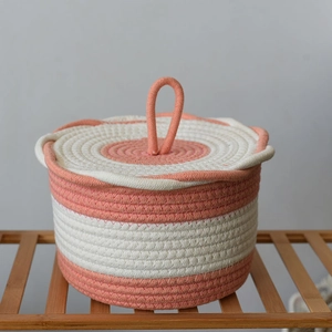Detail view of woven cotton rope storage basket with lid in peach orange stripe