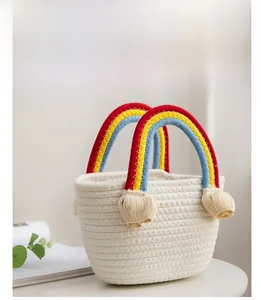 Detail of rainbow cotton rope handle and fringe on a cream handwoven straw beach basket