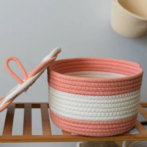 Detailed view of a round woven cotton rope storage basket with lid in pink stripes