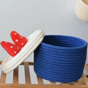 Detail of hand-woven navy cotton rope storage basket with red polka dot bow lid