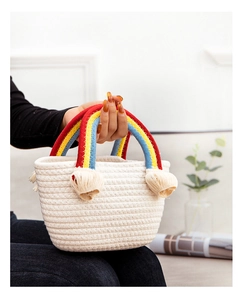 Detail of cream-white woven bag with rainbow cotton rope handles and decorative tassels