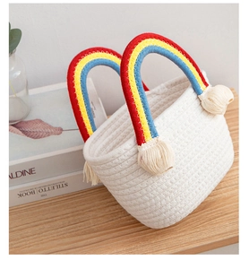 Detail of handmade woven cotton rope basket with vibrant rainbow handles and white tassels