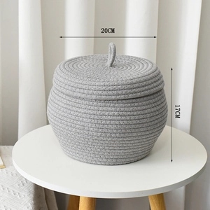 Detail of grey hand-woven cotton rope pumpkin basket with lid on minimalist table