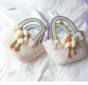 Detailed macro of handmade cotton rope woven bag with colorful rainbow handle and fabric flowers