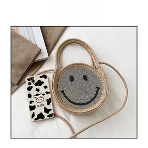 Vue détaillée du sac cabas en paille tressée avec smiley en sequins et un téléphone pour la taille