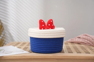 Detailed close-up of blue and white woven storage basket with a red polka dot bow decoration