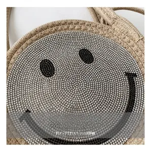 Détail d'un sac en paille tissé avec un motif smiley scintillant en strass
