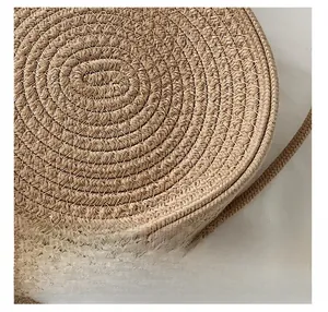 Détail de la texture tissée en paille d'un sac à bandoulière rond avec surpiqûres blanches