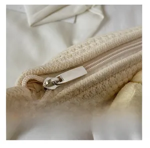 Detail view of the smooth silver metal zipper on the beige woven bucket bag with floral charm
