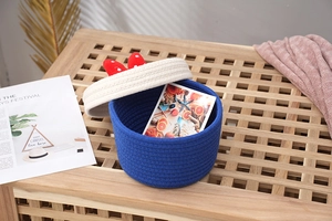 Detail of round cotton rope basket featuring a red polka dot bow on the cream-colored lid