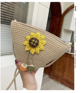 Detail of handmade straw crossbody bag featuring a large sunflower and mini pompom charms