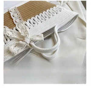 Detailed view of woven straw tote featuring contrast white cotton rope and lace bow