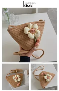 Close-up of khaki woven bucket bag featuring white fabric flower and pink cherry charms