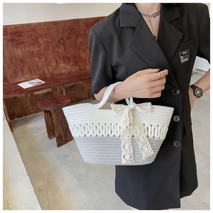 Detail view of woven tote bag with contrast wave texture and white lace bow accessory