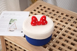 Detail of woven cylindrical storage basket with polka dot bow and cotton rope lid