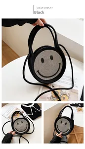 Détail du sac cabas en paille tissée noire avec un grand motif smiley en paillettes