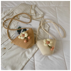 Detail of woven bucket bags with floral accents on white tweed fabric background