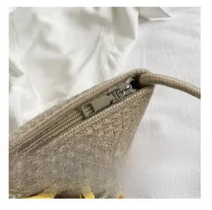 Detail of the smooth silver metal zipper and woven texture on a sunflower straw beach bag