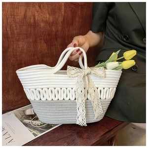 Detail of hand-woven rope tote bag with bicolor texture and delicate lace bow accent