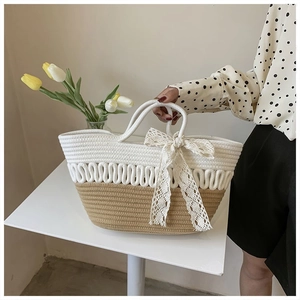 Detail of woven tote bag featuring creamy cotton rope waves and large lace bow decoration