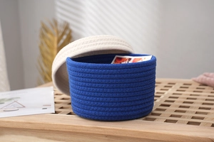 Detail of handwoven navy and cream cotton rope storage basket with a textured lid