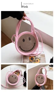 Détail du sac à main rose en paille tressée avec un motif smiley en strass