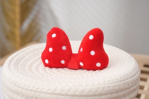 Detailed view of plush red and white polka dot bow accessory on a woven base