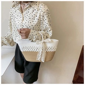 Detail view of woven handbag showing beige and khaki stitching with a white lace bow charm