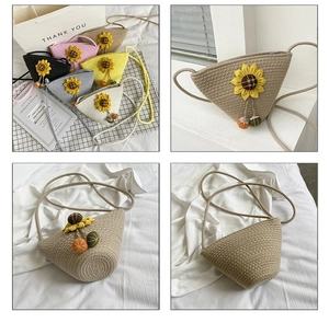 Detail view of woven straw crossbody bag with sunflower decor and small ball charms