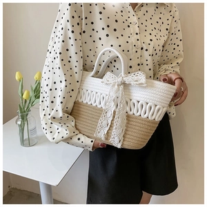 Close-up of woven straw tote bag with white lace bow and contrasting color textures